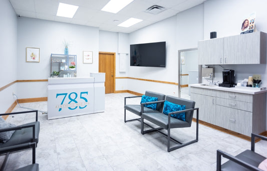 785 med spa waiting room with reception desk, chairs, and a TV.